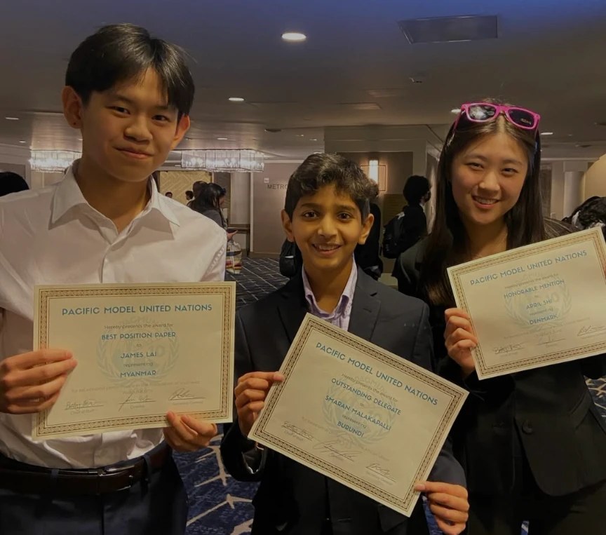 Smaran holding an Outstanding Delegate certificate from Pacific Model United Nations, with two teammates holding their awards
